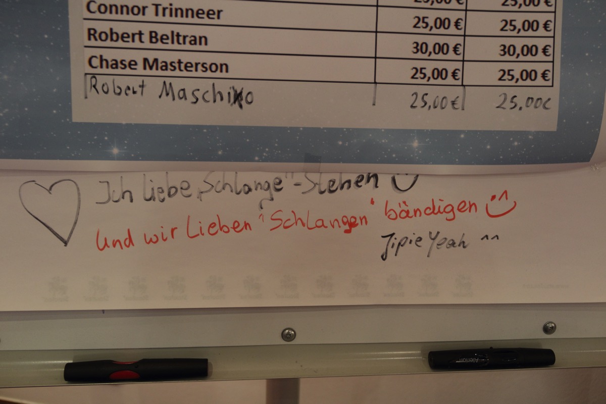 Handschrift, Ich liebe es, Schlange zu stehen. :-) Darunter in anderer Handschrift: Und wir lieben es, Schlangen zu bändigen, Yippiejayeah!